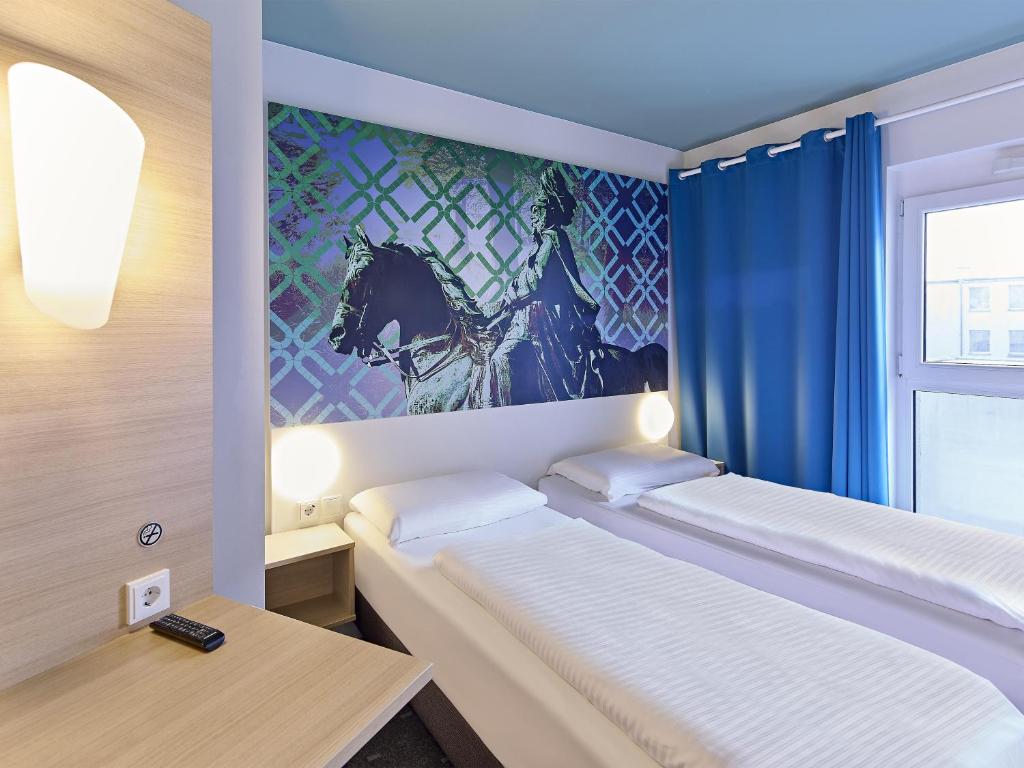 two beds in a small room with a window at B&B Hotel Dortmund-City in Dortmund