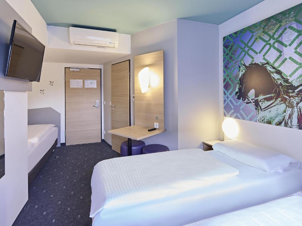 a hotel room with two beds and a desk at B&B Hotel Dortmund-City in Dortmund