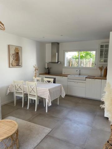 een witte keuken met een tafel en stoelen. bij Les Lodges de Saint Brice 2 in Arès