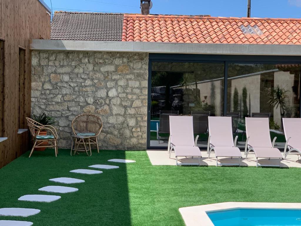 un patio con sillas de césped y una piscina en Adega D'Aldeia, 
