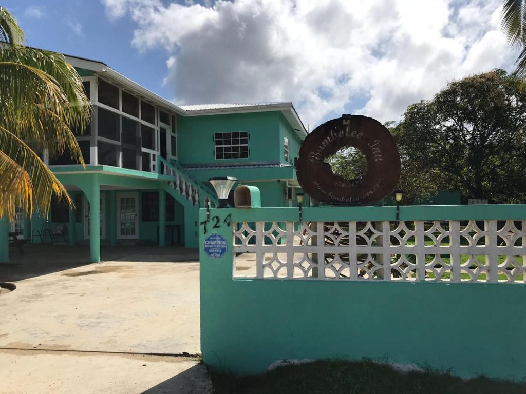 um edifício verde com uma cerca e um cartaz em Bamboleo Inn em Cidade de Belize