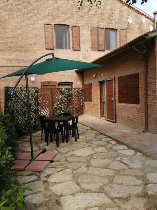 un patio con una mesa y una sombrilla verde en Casa Sant'Eurosia, immergiti nella Maremma Toscana, en Principina Terra