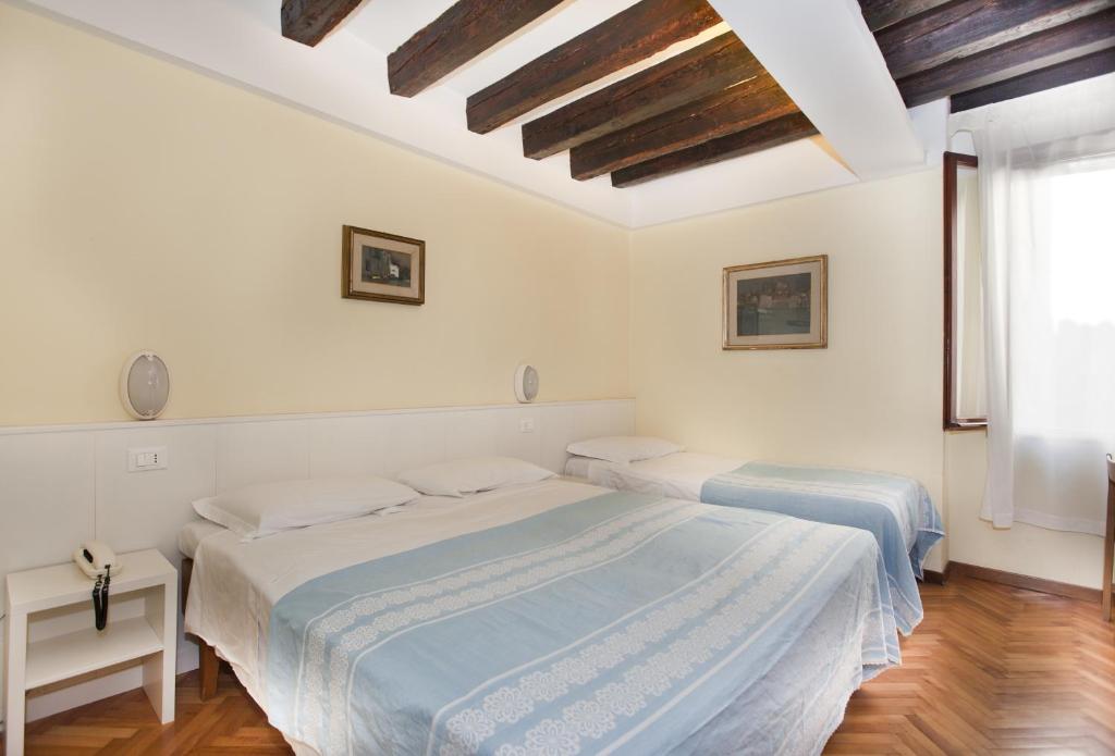 two beds in a white room with wooden floors at Hotel San Fantin in Venice