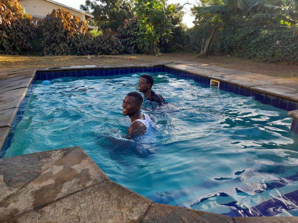 two men swimming in a swimming pool at 56 Archer Crescent Mainhouse in Durban