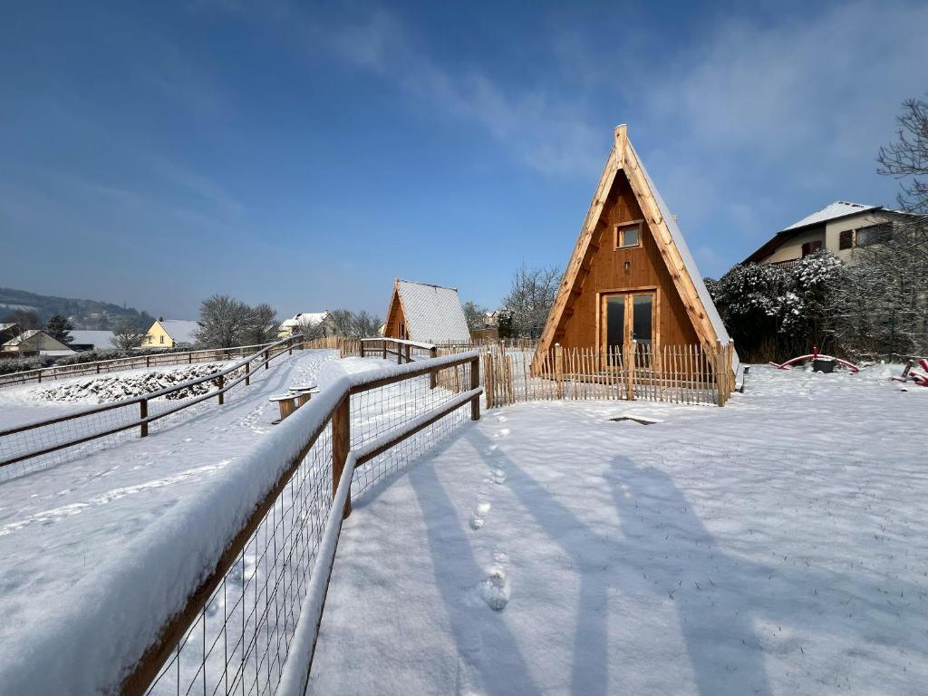 een houten huis met een hek in de sneeuw bij Tiny House Ardennes in Fromelennes