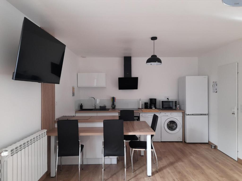 a kitchen with a table and chairs and a refrigerator at Appartement T2, avec Terrasse. in La Roche-sur-Yon