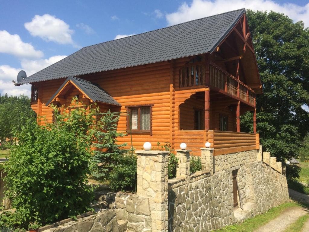 a log cabin with a stone wall in front of it at Villa PidStromom in Mykulychyn