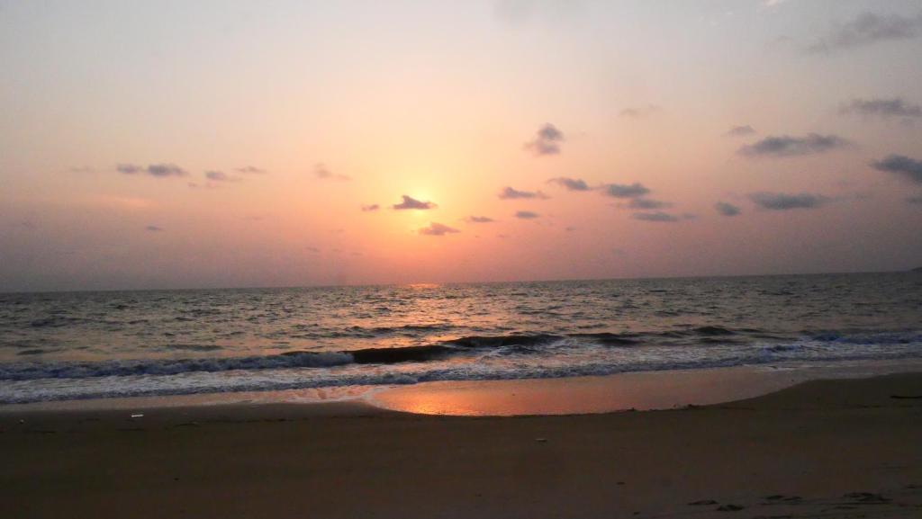 um pôr do sol na praia com o oceano em Résidence Tropicale em Libreville