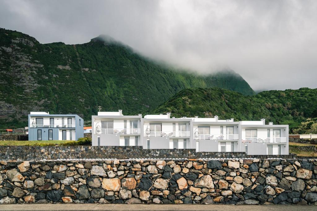 a group of white buildings in front of a mountain at Villas do Mar in Faja Grande