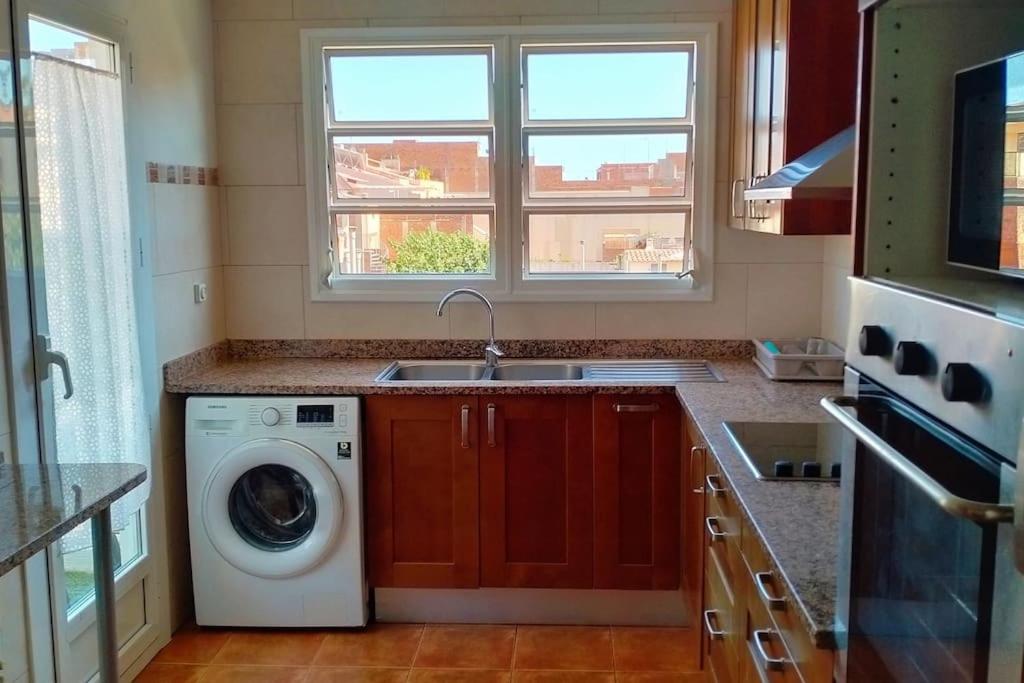 een keuken met een wasmachine en een wastafel bij Apartamento céntrico cerca de la playa in Malgrat de Mar