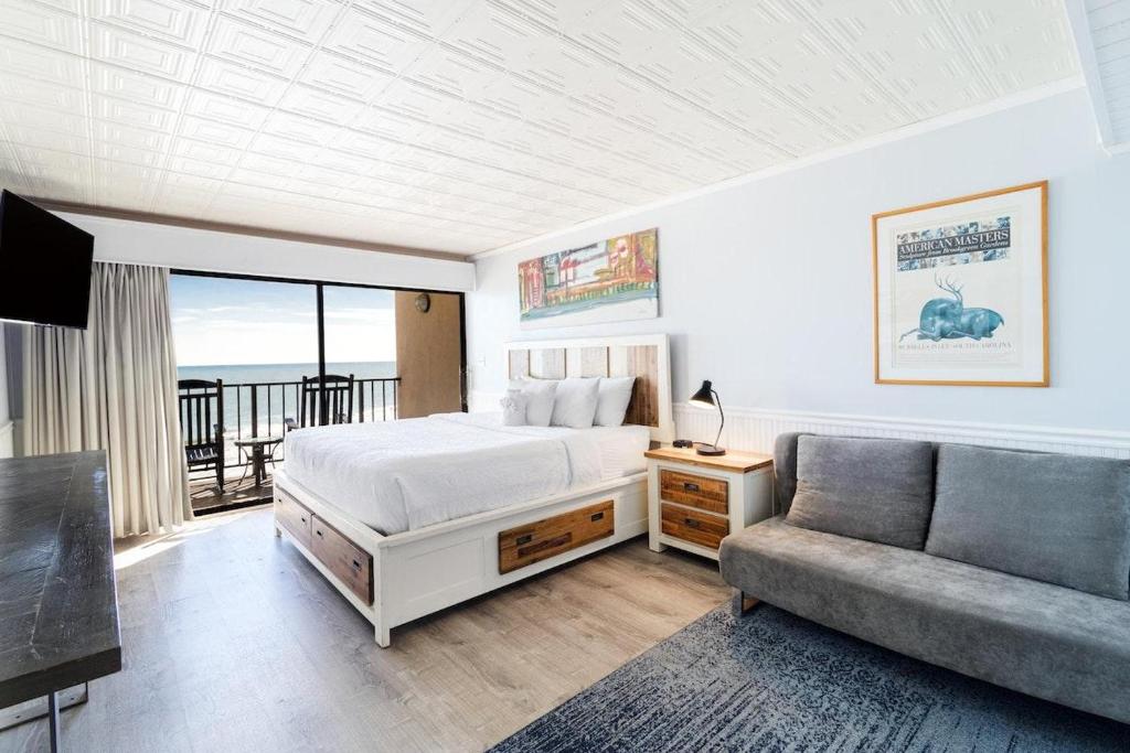 un dormitorio con una cama y un sofá en Lovely Oceanfront King Room 5th Flr, en Pawleys Island