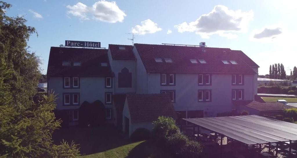 a large white building with a red roof at Parc Hôtel in Carvin