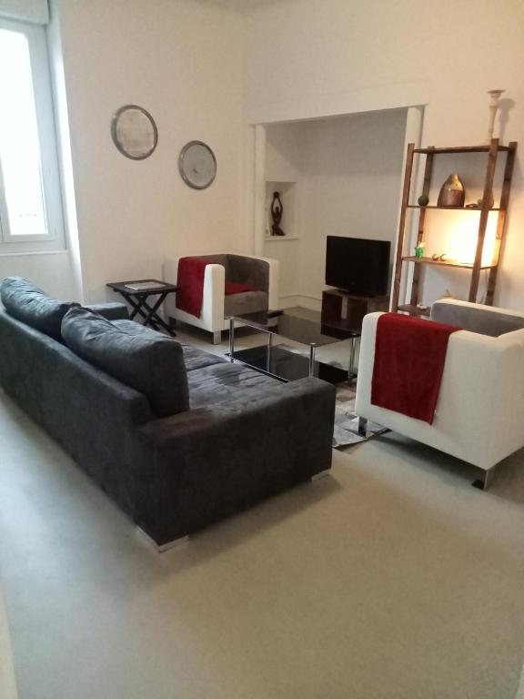 a living room with two couches and a tv at Logement spacieux et lumineux in Montceau-les-Mines