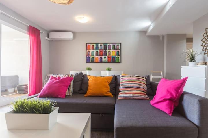 sala de estar con sofá gris y almohadas coloridas en Golf Lucentum, en Alicante