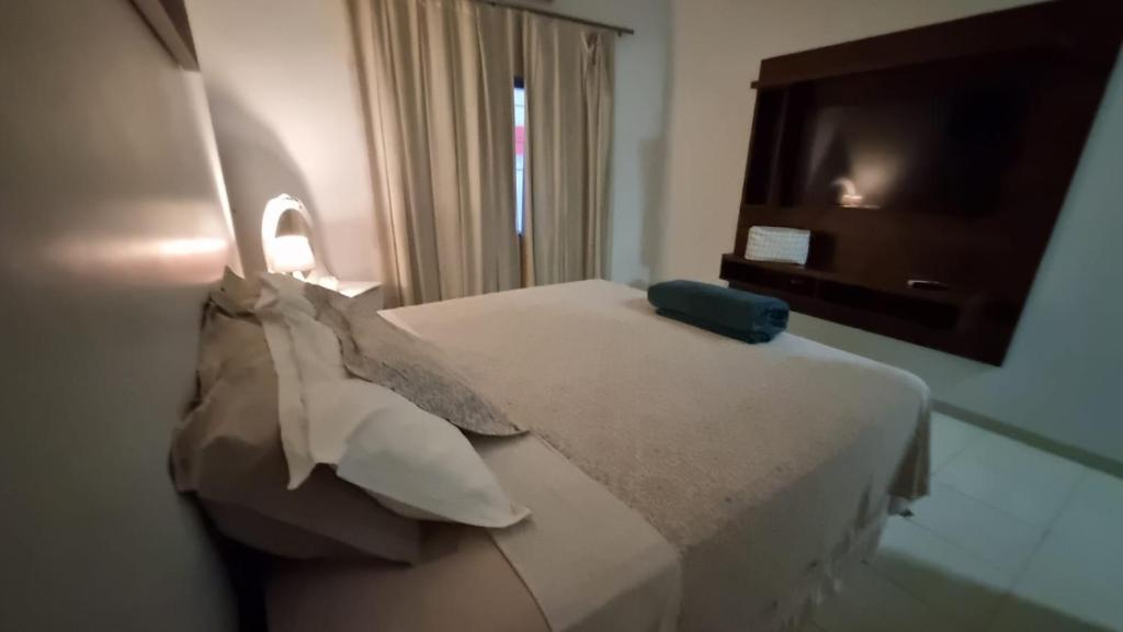 um quarto de hotel com uma cama com almofadas e uma televisão em Apartamento Confortável e Espaçoso em Sinop