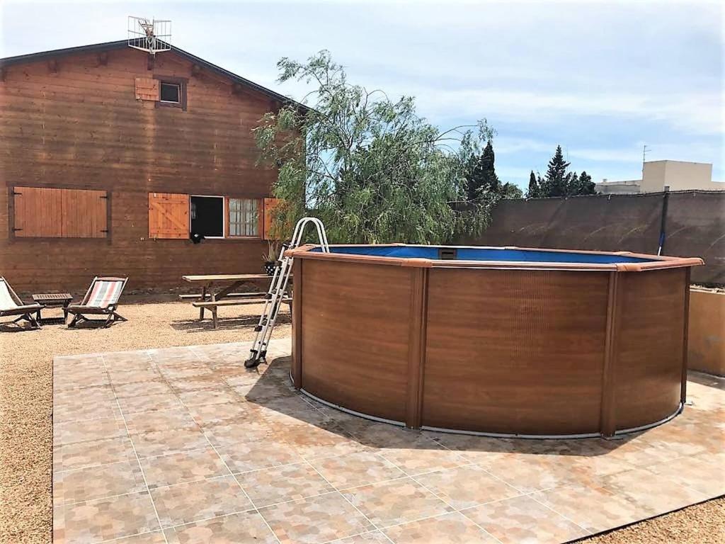 uma banheira de hidromassagem num pátio ao lado de um edifício em Carmeta - Casa Rural de madera con jardín, piscina privada y barbacoa - Deltavacaciones em L'Eucaliptus