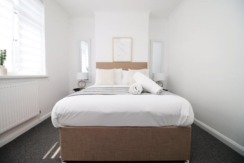 una camera da letto con un grande letto e pareti bianche di Bristol Street 2 BR FREE onsteet parking a Newport