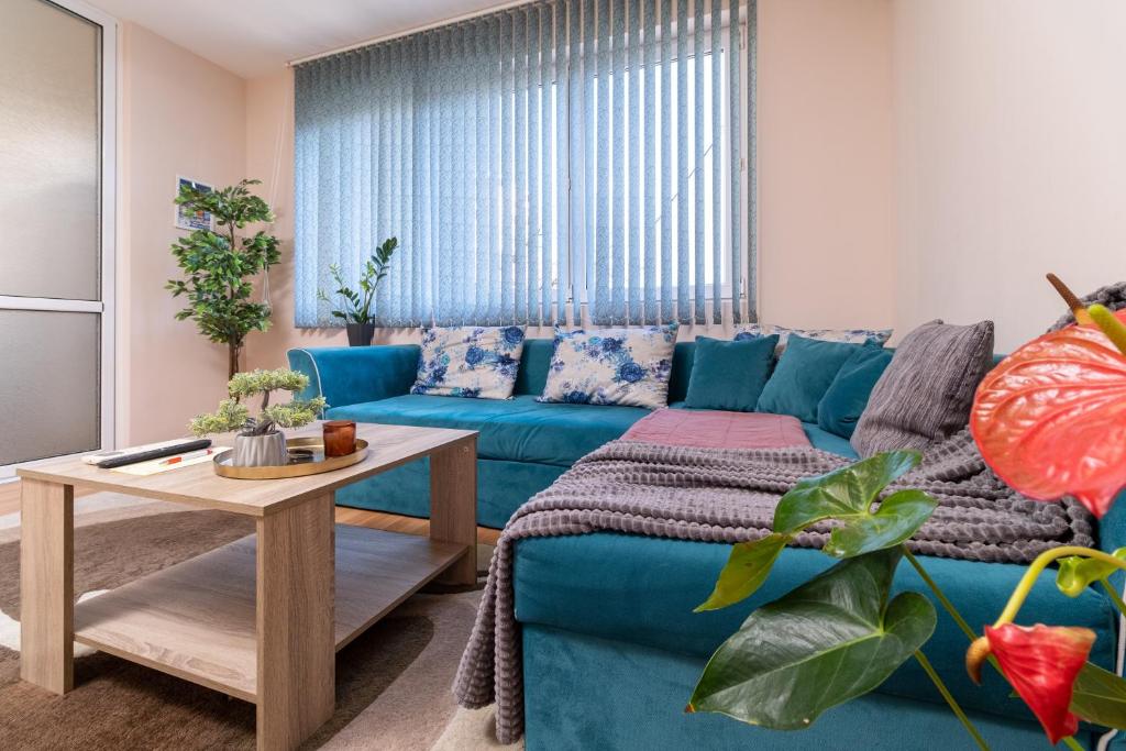 a living room with a blue couch and a table at Chic Urban Retreat: Modern 2-Bedroom Gem for Your City Escape in Plovdiv