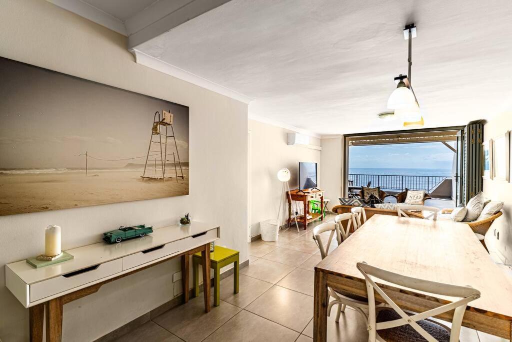 a dining room and living room with a view of the ocean at Sunny Beach Front Apartment in Ballito