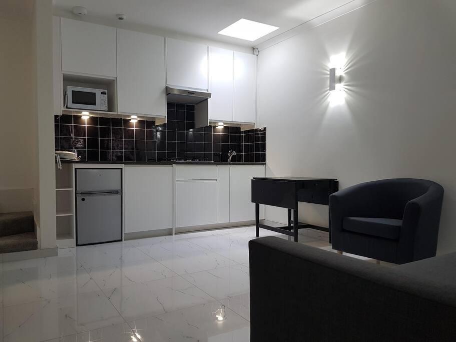 a kitchen with a couch and a chair in a room at Contemporary ground flr maisonette- Entire place in Northwood