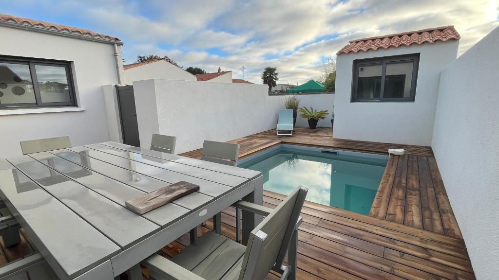 un patio avec une table et une piscine dans l'établissement Maison Liséna, à Périgny
