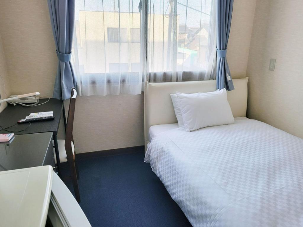 Cette petite chambre comprend un lit et une fenêtre. dans l'établissement Okasan Hotel - Vacation STAY 60555v, à Ōgaki