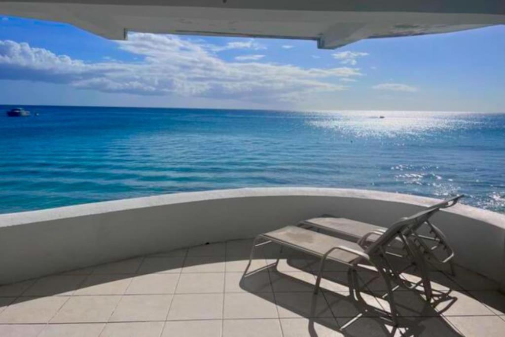 una silla sentada en un balcón con vistas al océano en Purple Rain - Direct Beach Access, 2 Bedroom, 2 Terrace Holiday Home Bliss, en Saint Peter