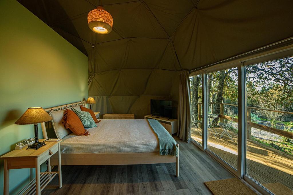 a bedroom in a tent with a bed and a desk at Manteiros Glamping in Canas de Senhorim