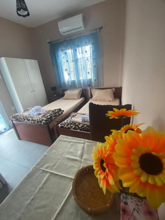 een kamer met 2 bedden en een vaas met bloemen op een tafel bij Dimitris Rooms in Asvestokhórion