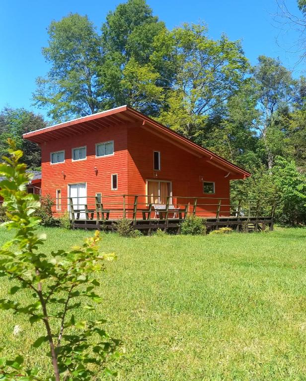 a red barn in the middle of a field at Cabaña Rincón Verde in Villarrica
