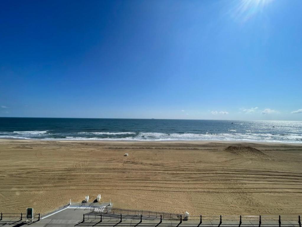 a group of people standing on a beach near the ocean at Playing Hooky at Dolphin Run-Oceanfront Condo-Pool in Virginia Beach