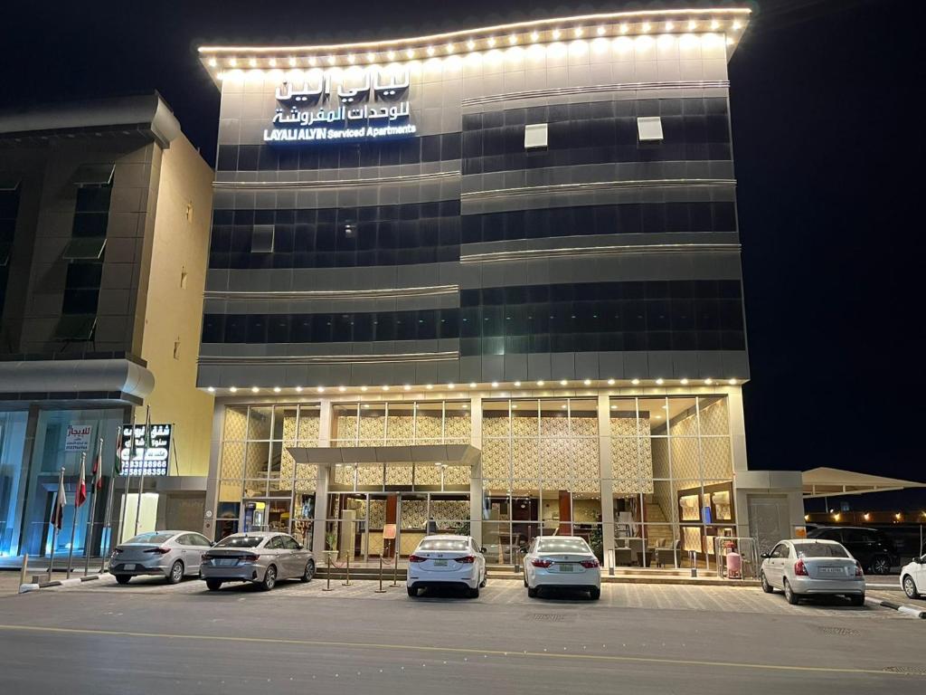 a large building with cars parked in a parking lot at ليالي الين للشقق المخدومة in Buraydah