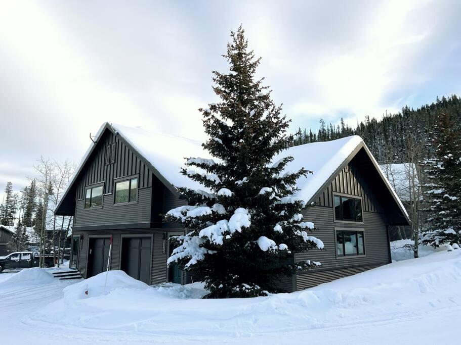 a house with a snow covered tree in front of it at 100 Steps Away Ski in Ski Out Condo in Big Sky