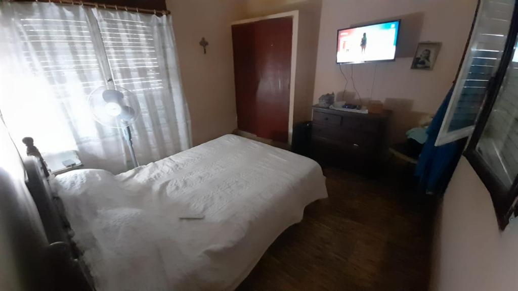 1 dormitorio con 1 cama blanca y TV en Tolita en Villa del Totoral