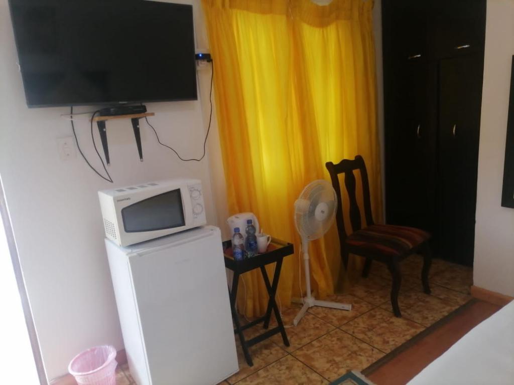 een kamer met een magnetron en een tafel met een stoel bij Ezamampondo Guest House in Koning Willemstad