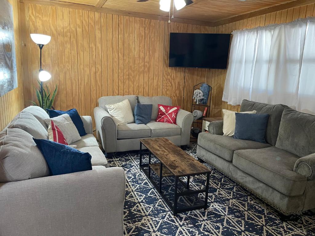 a living room with couches and a flat screen tv at Bixby Cove Cabin #1 in Porum