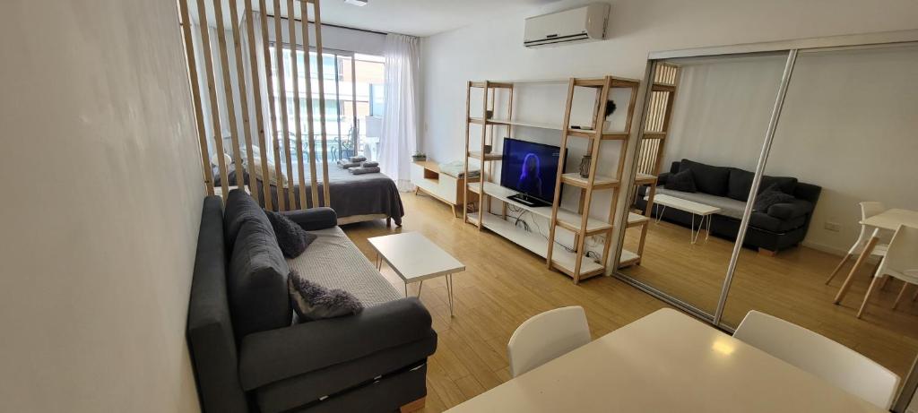 een woonkamer met een bank, een tafel en een televisie bij Palermo Premium, Piso alto con amplio balcon, pileta en terraza, Gym y laundry in Buenos Aires
