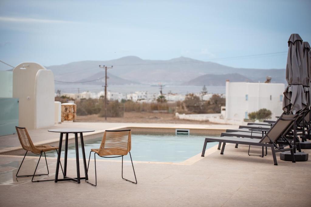 a table and chairs next to a swimming pool at Anais Of Naxos in Agia Anna Naxos