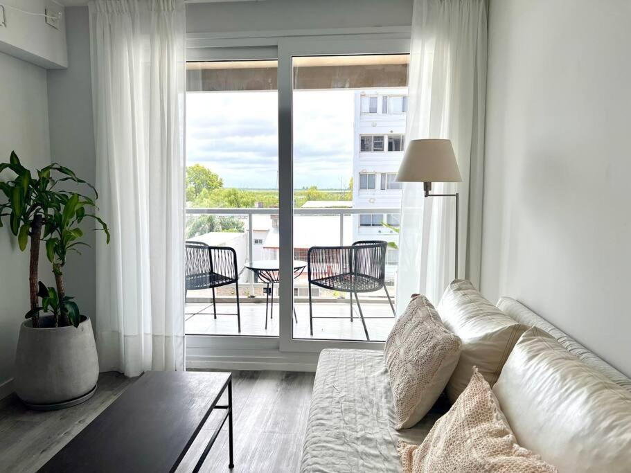 a white living room with a couch and a balcony at Depto con vista al río Paraná. in San Nicolás de los Arroyos