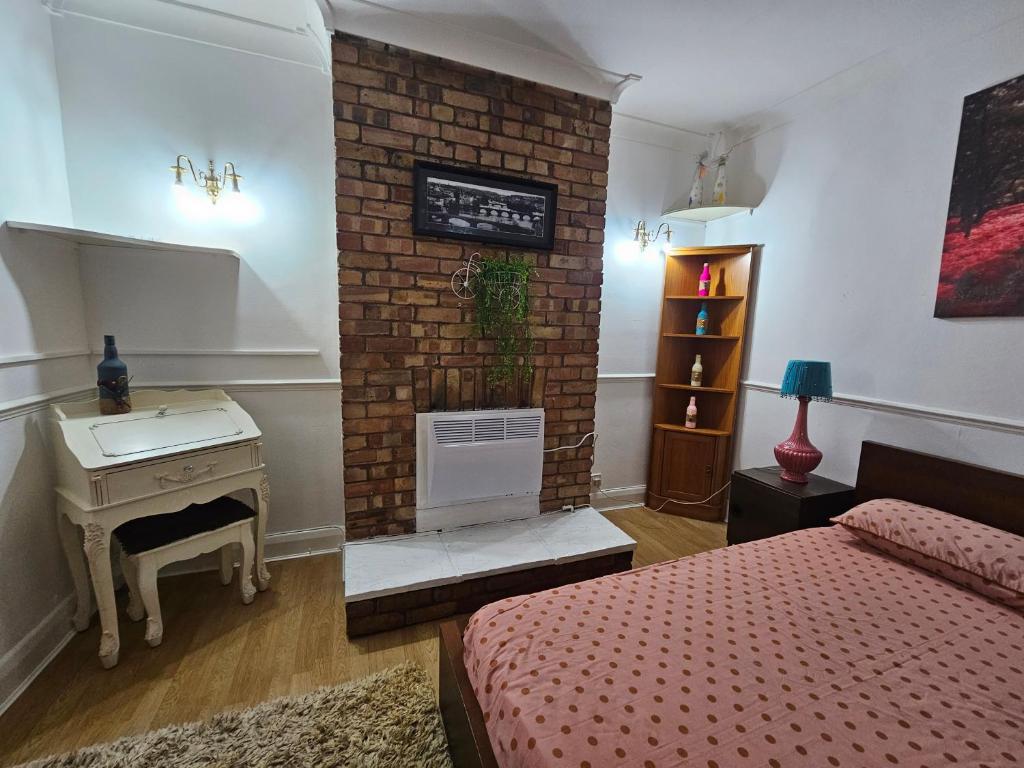 ein Schlafzimmer mit einem gemauerten Kamin, einem Bett und einem Schreibtisch in der Unterkunft 1 Beautiful large room in Goodmayes