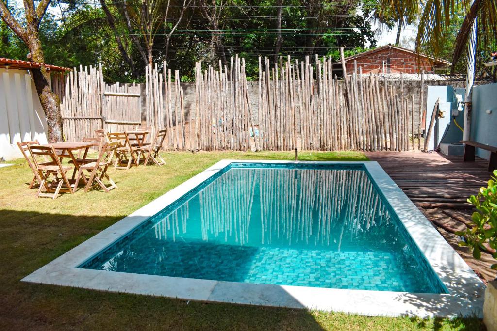 a swimming pool in a yard with chairs and a fence at Caminho do Paraíso in Porto De Galinhas
