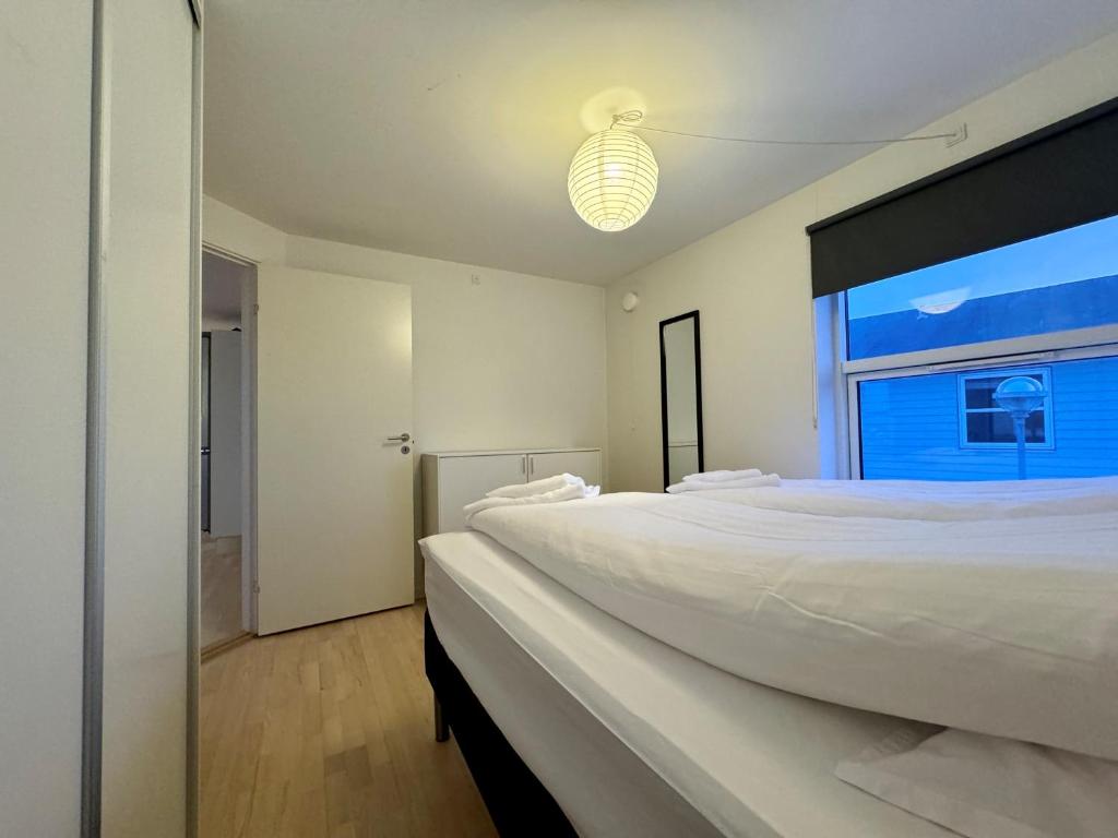 a white bedroom with a large bed and a window at Hotel Nuka in Ilulissat