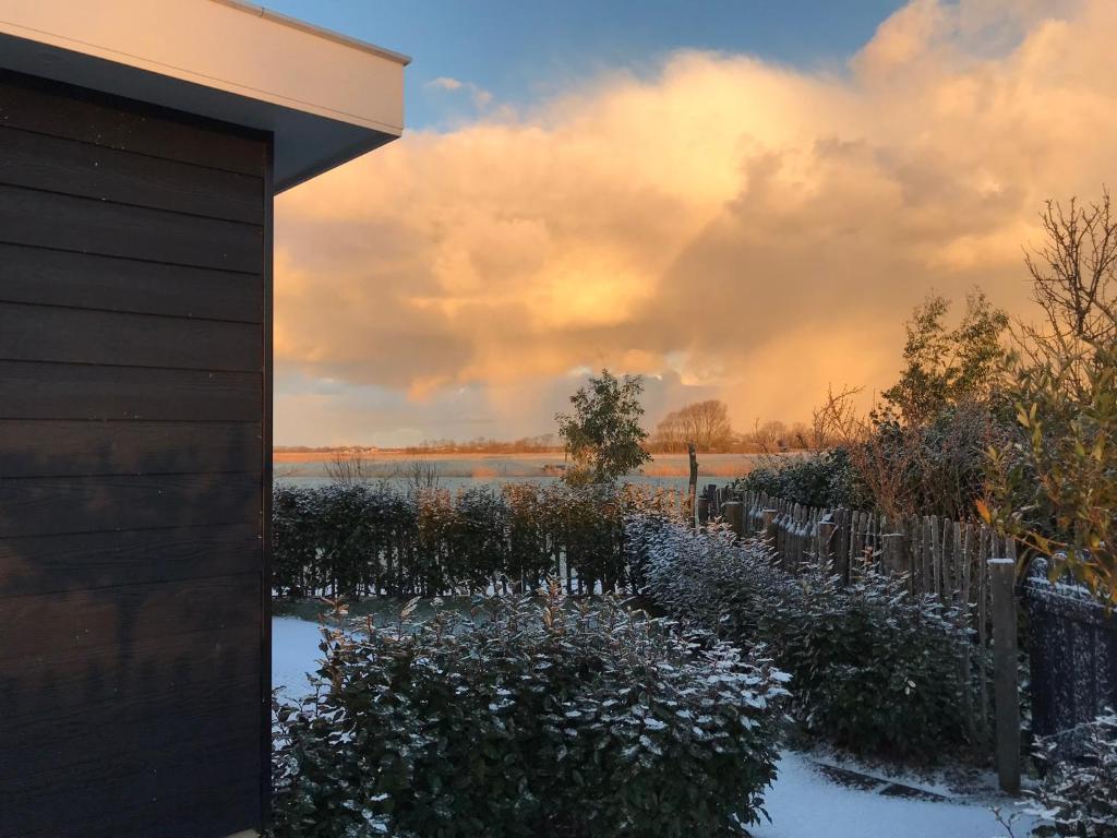 una casa con nieve en el suelo junto a una valla en Appartement, en Meliskerke