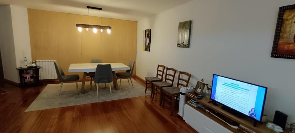 uma sala de estar com uma mesa e cadeiras e uma televisão em Private Bathroom Room Shared Kitchen no Porto
