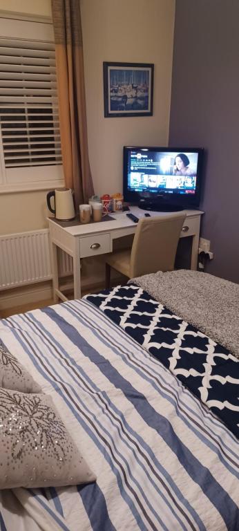 um quarto com uma cama e uma secretária com uma televisão em Aylesbury Lovely Double and Single Bedroom with Guest only Bathroom em Buckinghamshire