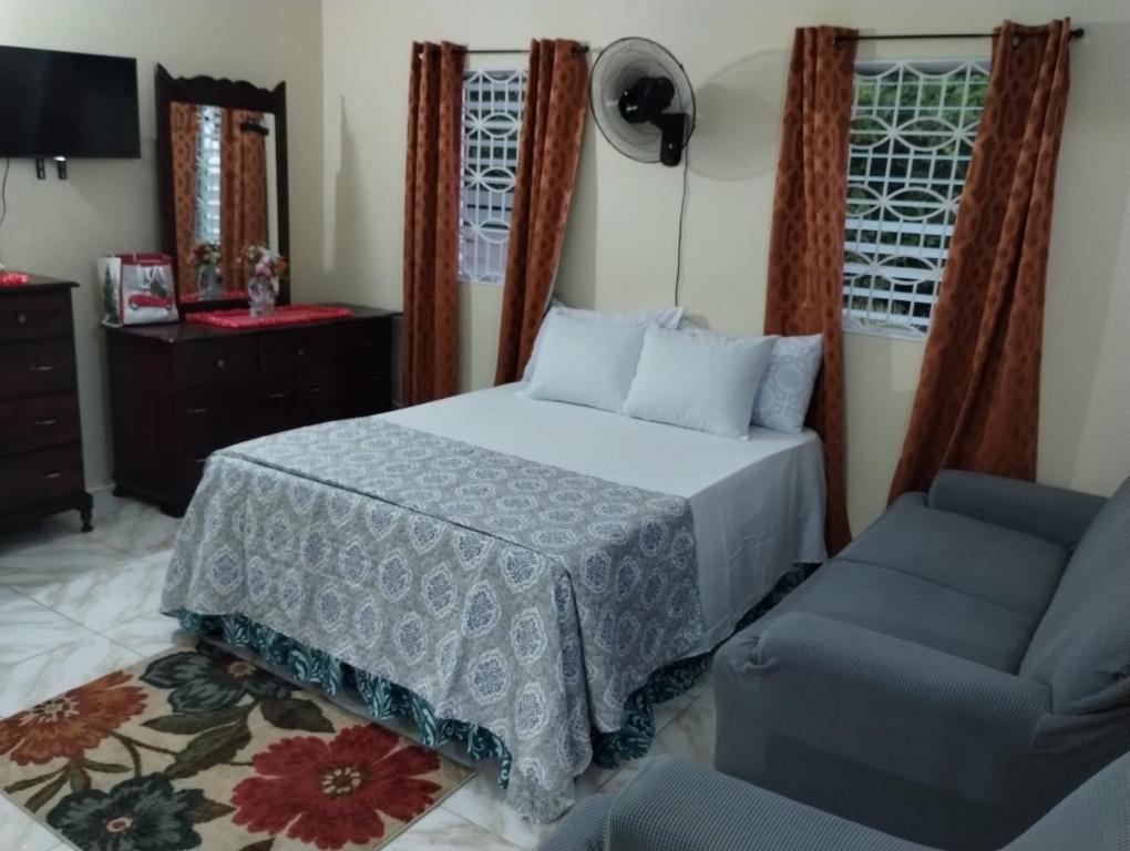 um quarto com uma cama e uma cadeira em Diana's Portmore Retreat em Portmore