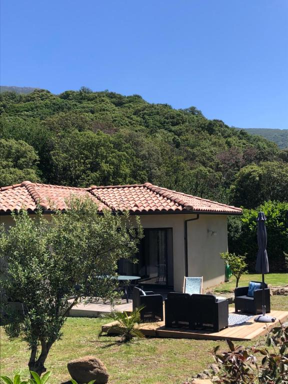 una casa con sillas y un paraguas en un patio en Casuccia Eva maria, en Patrimonio