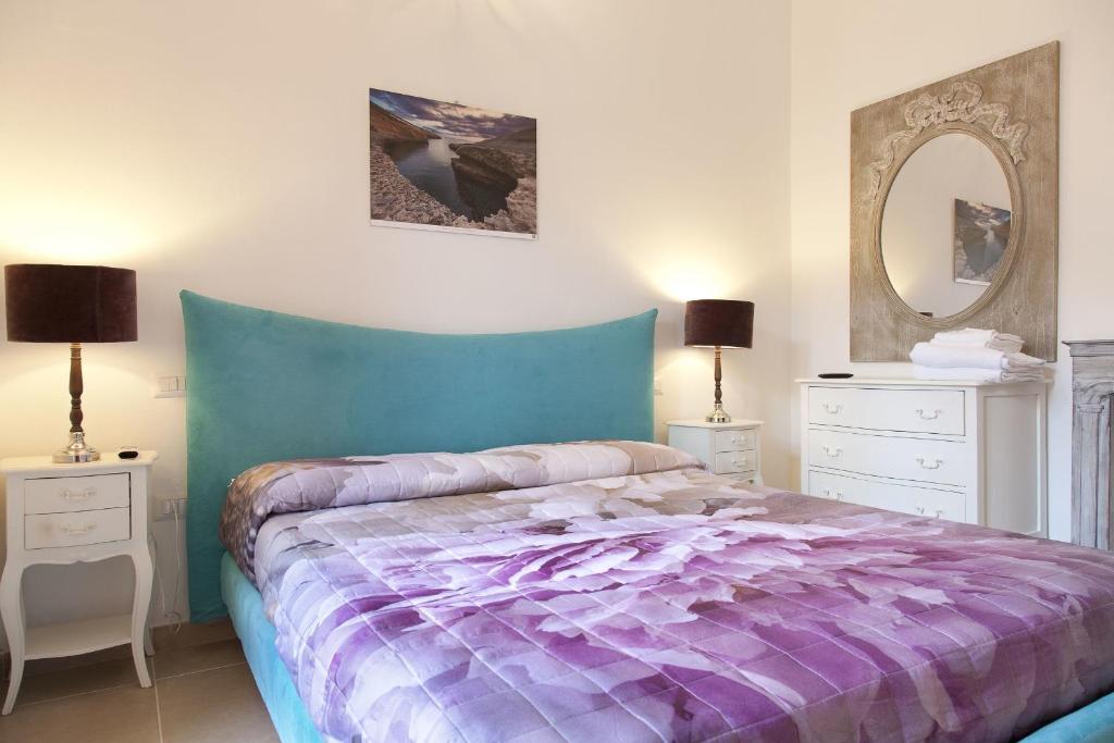 a bedroom with a purple bed with two dressers and a mirror at Guest house Acuario in Torre Grande