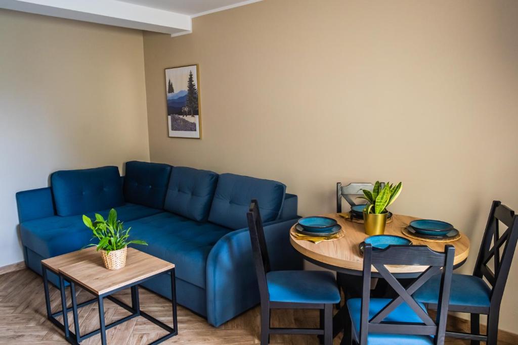 ein Wohnzimmer mit einem blauen Sofa und einem Tisch in der Unterkunft Pokoje Siódemka in Stegna