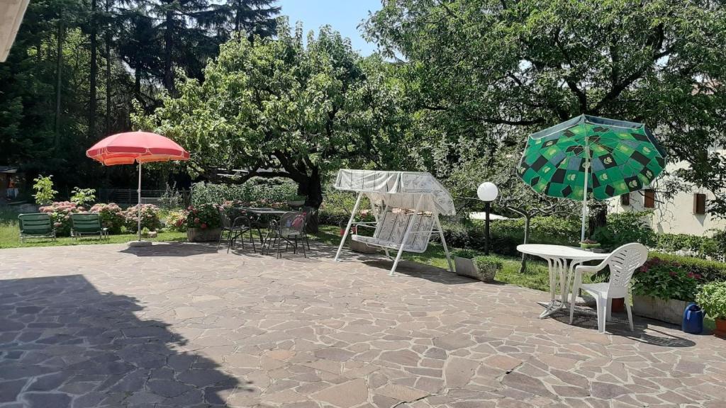 een patio met tafels en stoelen en een parasol bij Appartement in San Zeno Di Montagna mit Terrasse und Garten und Seeblick in San Zeno di Montagna